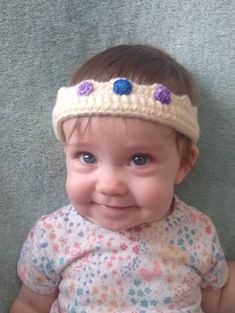 a smiling baby wearing a crocheted headband