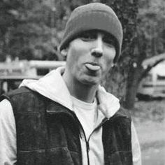 a man in a hat is making a funny face with his tongue out while wearing a vest