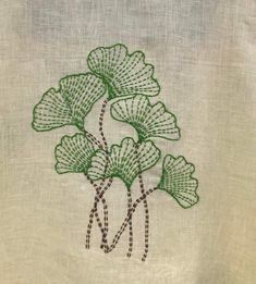 a close up of a piece of cloth with green embroidery on the front and back