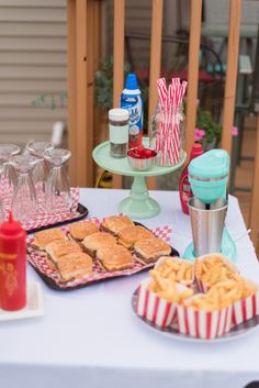 a table topped with plates of food next to cups and glasses on top of a table