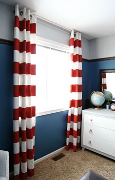 a living room with blue walls and red and white striped curtains on the windowsill