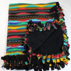 a multicolored blanket with fringes on it sitting on top of a white surface