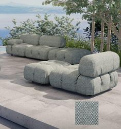 a couch and chair sitting on top of a cement floor next to a body of water