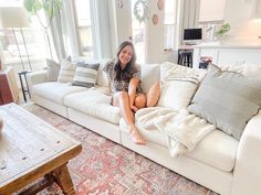 a woman sitting on top of a white couch in a living room