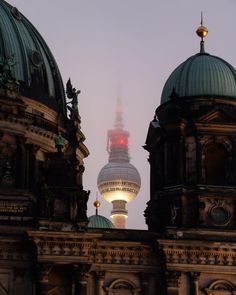 the top of two buildings with dome tops and lights on at night in berlin, germany