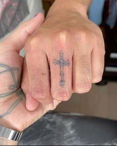 a person with a cross tattoo on their finger and ring in the middle of his hand