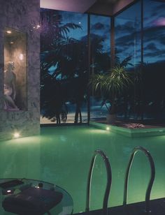 an indoor swimming pool at night with the lights on