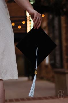 a person holding a graduation cap and tassel in their left hand while walking down the street