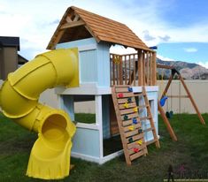 a child's play house with a slide and climbing frame in the grass next to it