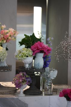 there are many flowers in vases sitting on the counter next to each other,