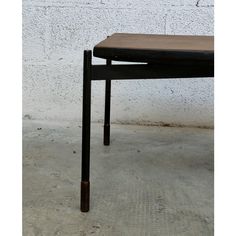 a wooden table sitting in front of a white wall with a black metal frame on it