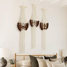 three wall hangings above a bed in a room with white walls and wooden furniture