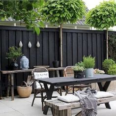 an outdoor table and bench with potted plants