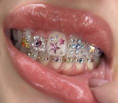 a close up of a person's teeth with different colored and shaped jewels on them