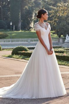 a woman in a white wedding dress standing outside