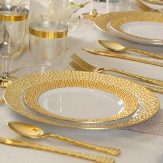 the table is set with gold and white plates, silverware, and napkins