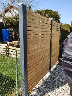 a fence that is made out of wooden slats and metal posts, along with gravel