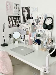 a white desk topped with a laptop computer next to a pink pillow and headphones