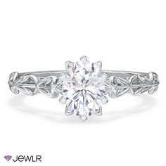 a white gold engagement ring with an oval cut diamond in the center and leaves around it