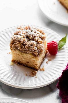 a piece of cake sitting on top of a white plate next to a raspberry