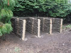 a row of wooden posts sitting in the middle of a dirt field next to trees