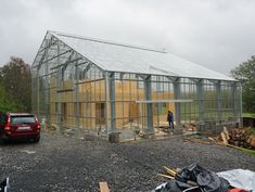 a man standing in front of a building with a green roof and glass walls on it