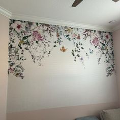 a bed room with a ceiling fan and flowers on the wall