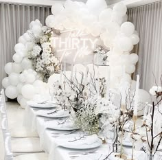 a table set up for a party with white balloons