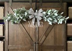 a wooden door decorated with greenery and a bow for the entrance to a store