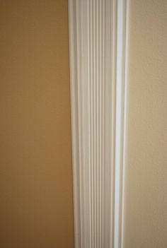 the corner of a room with a white radiator and tan walls in it