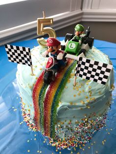 a birthday cake decorated with mario kart and rainbow streamers