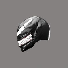 a black helmet with white teeth and fangs on the face is shown in front of a gray background