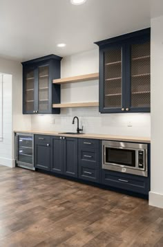 an empty kitchen with blue cabinets and wood floors