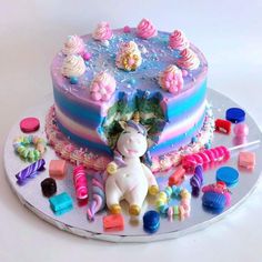 there is a cake decorated with candy and a unicorn on the top, surrounded by candies