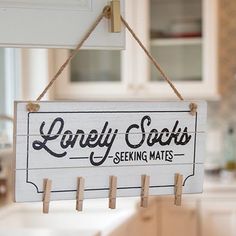 a wooden sign hanging from the side of a kitchen wall that says lonely socks seeking mates