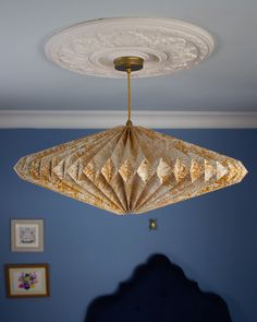 a light fixture hanging from the ceiling in a room with blue walls and pictures on the wall