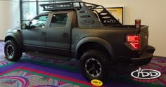 a black truck parked in front of a window next to a colorful carpeted floor