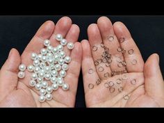 two hands are holding small white pearls and silver rings in their palms, while the other hand is full of smaller beads