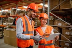 two people in orange safety vests looking at something on a tablet