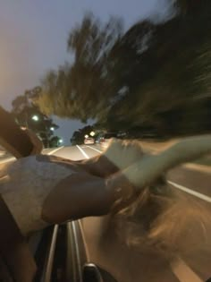 the woman is driving down the street in her car at night time, with motion blurry