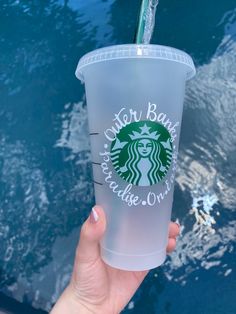 a starbucks cup with a straw in it is held up by someone's hand