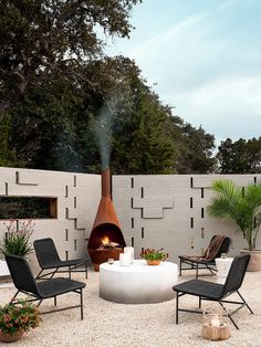 an outdoor fire pit with chairs around it