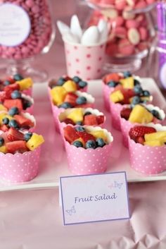 small cups filled with fruit salad on top of a white plate next to other desserts