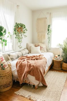 a bedroom with white walls and plants in the window sill, rugs on the floor