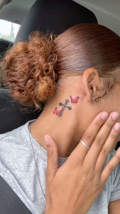 a woman with a cross tattoo on her neck is sitting in the back seat of a car