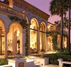 an elegant mansion with columns and arches lit up at night