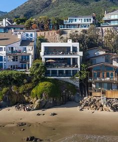 an aerial view of houses on the beach with mountains in the background