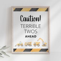 a framed sign that says caution terrible twos ahead with construction vehicles in the background