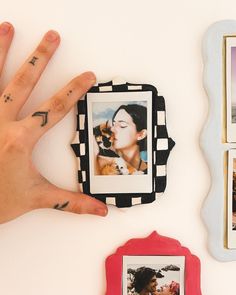 a person's hand with tattoos on their fingers next to some pictures and frames