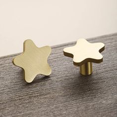 two gold and silver star shaped knobs on a wooden surface with white wall in the background